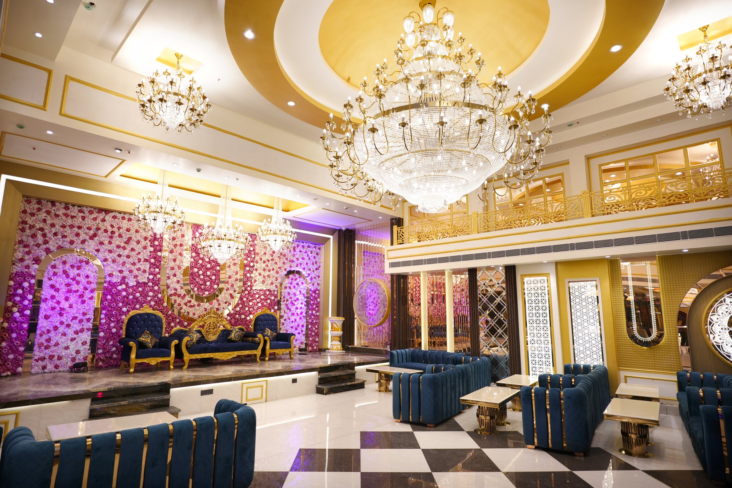 Royal wedding hall interior with grand chandeliers, floral stage backdrop and luxury teal seating at The Great Palace Banquet Hall, East Delhi