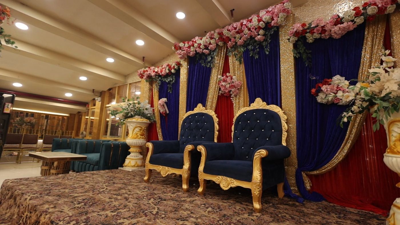 Royal wedding ceremony stage with blue velvet throne chairs and gold curtain floral backdrop at The Great Palace Banquet Hall